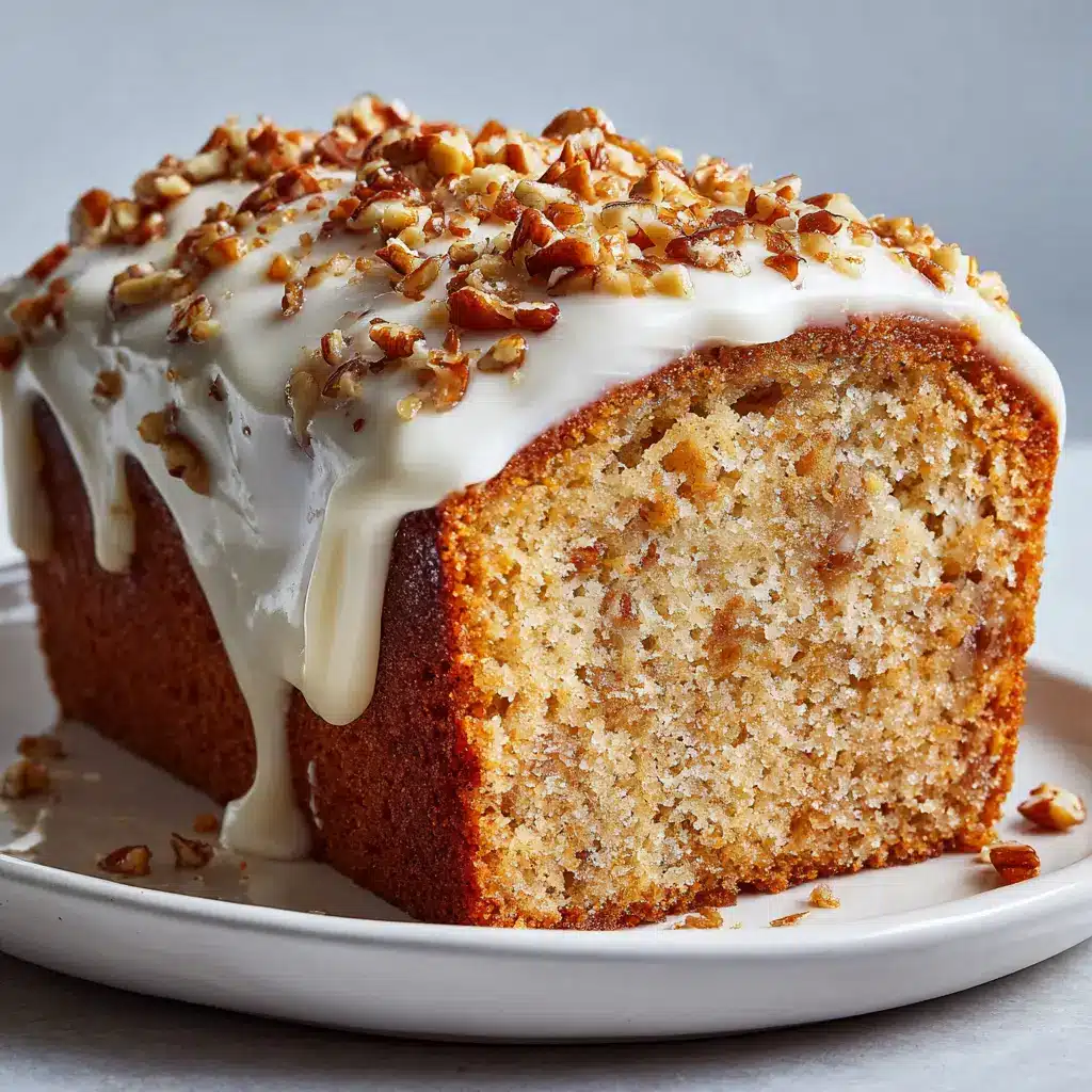 The Ultimate Butter Pecan Loaf Cake 2 A slice of moist, golden-brown butter pecan loaf cake resting on a plain white dessert plate in soft daylight.