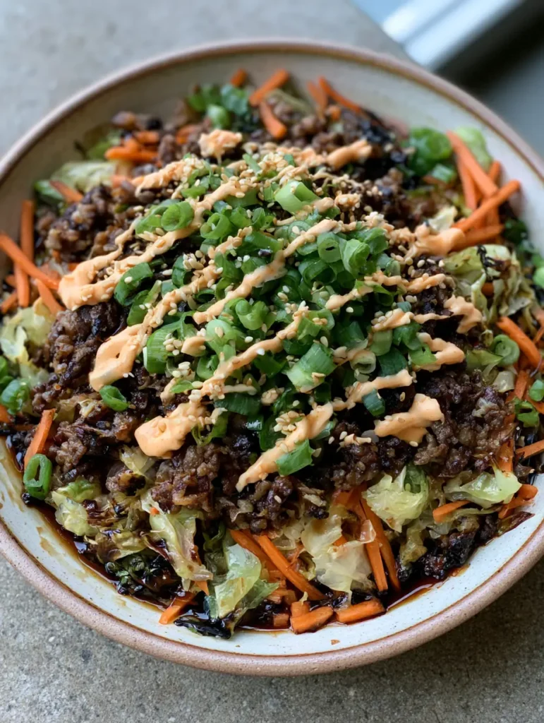 Egg Roll in a Bowl garnished with bright green scallions and white sesame seeds on a stone surface.