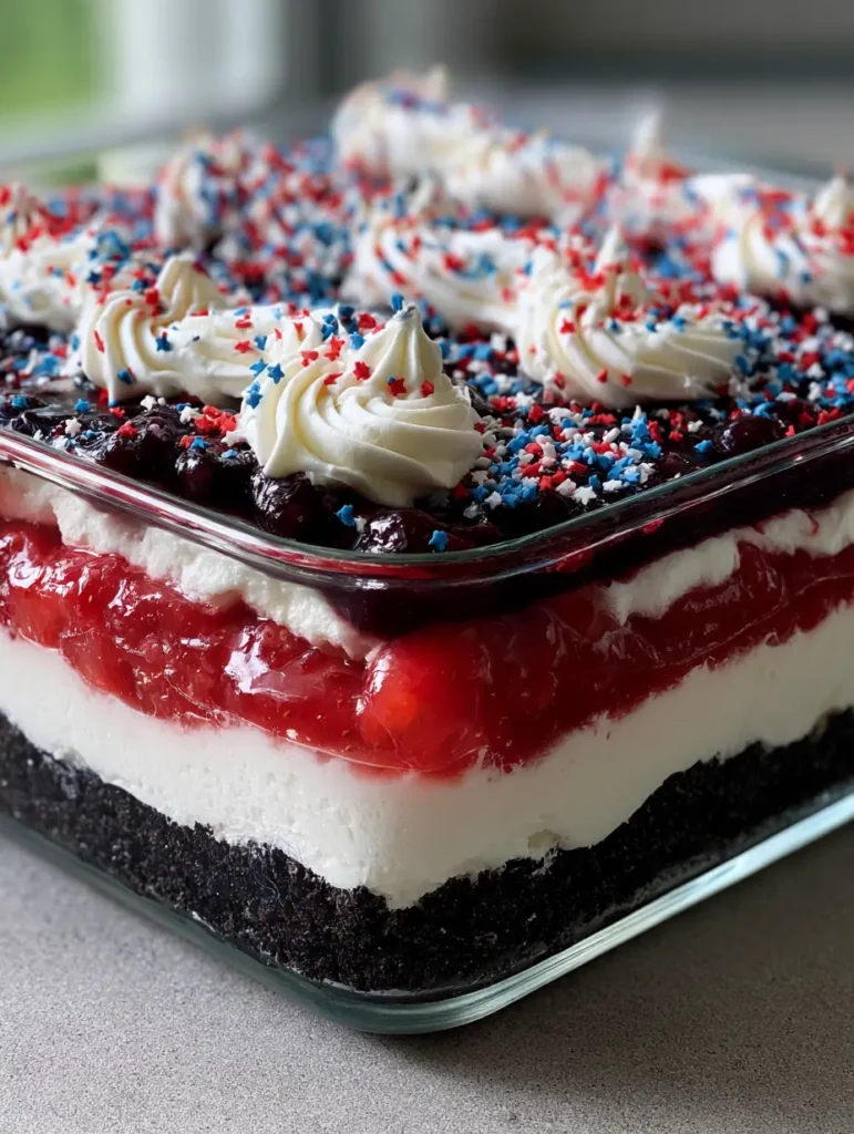 4th of July Dessert Lasagna: The Ultimate Patriotic Layered No-Bake Treat 1 Close up side view of 4th of July Dessert Lasagna showing the chocolate cookie crust and fruit layers.
