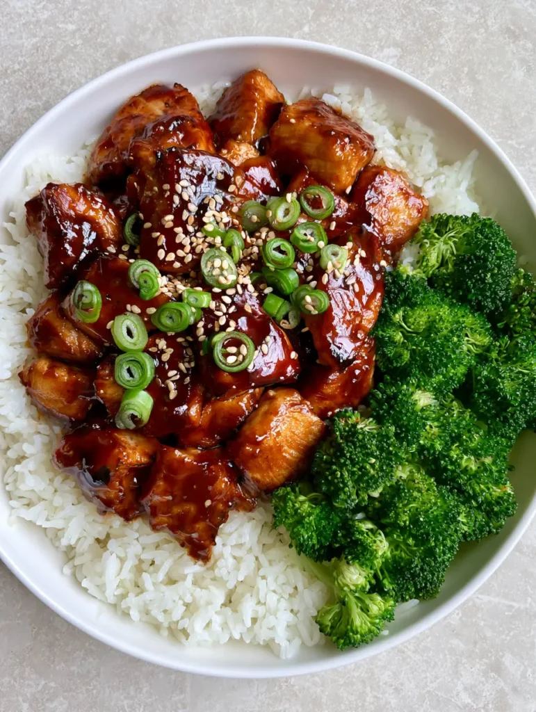 Teriyaki Chicken Bowl with Glossy Amber Glaze and Steamed Broccoli 2 Close up of seared chicken breast chunks with a thick reflective dark amber teriyaki glaze. (Teriyaki Chicken Bowl)